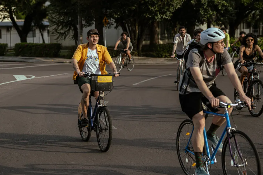 Ciclistas pedalando em uma rua arborizada